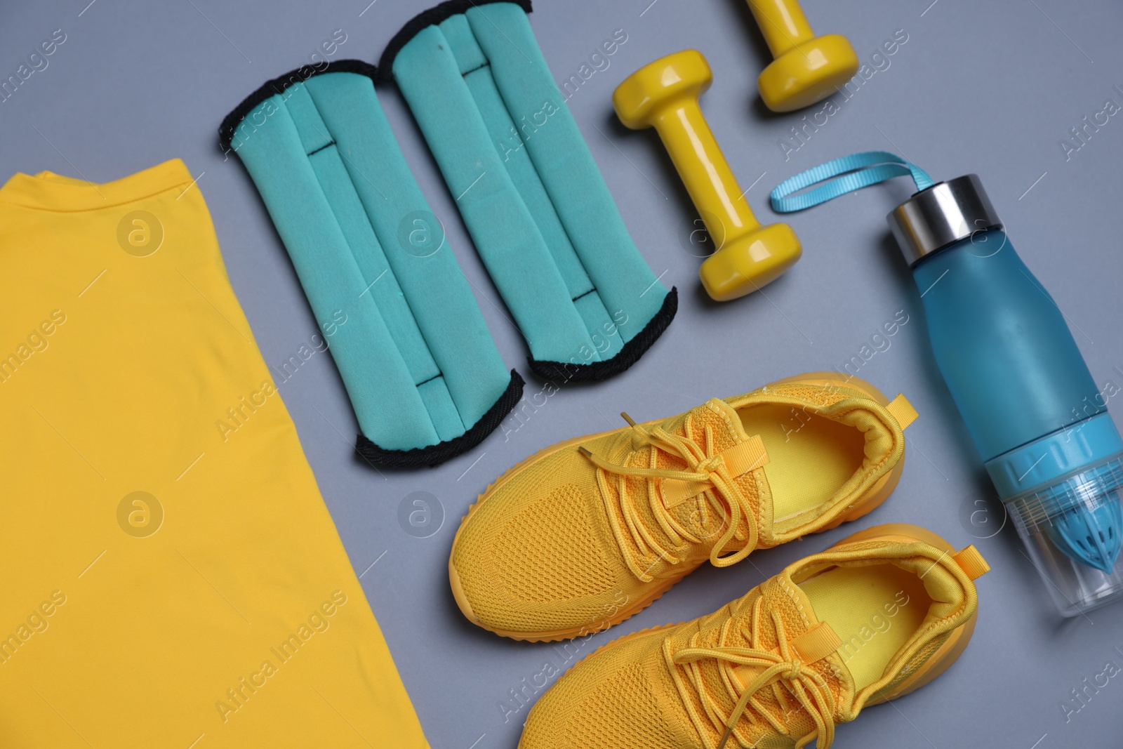 Sportswear, ankle weights, water bottle and dumbbells on grey background, flat lay Photo of Sportswear, ankle weights, water bottle and dumbbells on grey background, flat lay