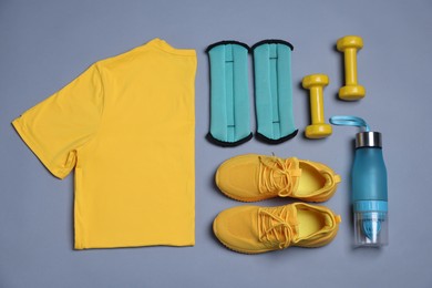 Photo of Sportswear, ankle weights, water bottle and dumbbells on grey background, flat lay