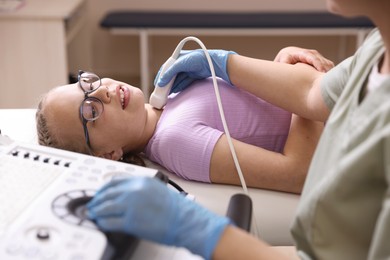 Photo of Sonographer conducting girl's thyroid gland ultrasound examination in clinic, closeup
