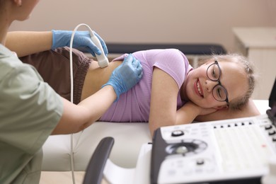 Photo of Sonographer conducting girl's renal ultrasound examination in clinic, closeup