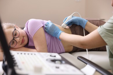 Photo of Sonographer conducting girl's renal ultrasound examination in clinic, closeup