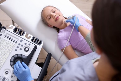 Photo of Sonographer conducting girl's thyroid gland ultrasound examination in clinic, above view
