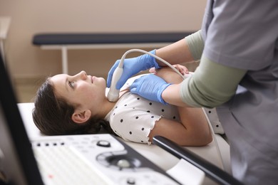 Photo of Sonographer conducting girl's thyroid gland ultrasound examination in clinic, closeup