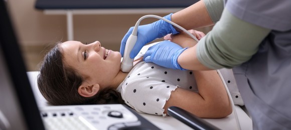 Photo of Sonographer conducting girl's thyroid gland ultrasound examination in clinic, closeup