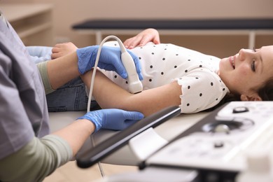 Photo of Sonographer conducting ultrasound examination of girl's arm in clinic, closeup
