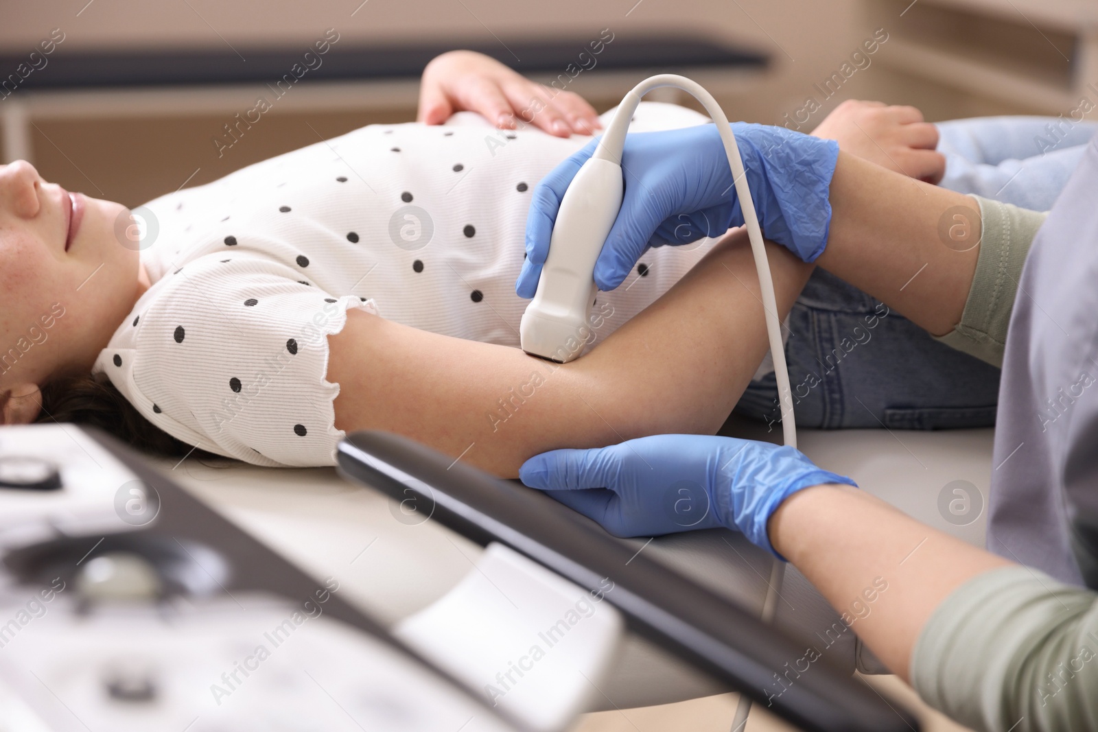Sonographer conducting ultrasound examination of girl's arm in clinic, closeup Photo of Sonographer conducting ultrasound examination of girl's arm in clinic, closeup