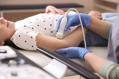 Photo of Sonographer conducting ultrasound examination of girl's arm in clinic, closeup