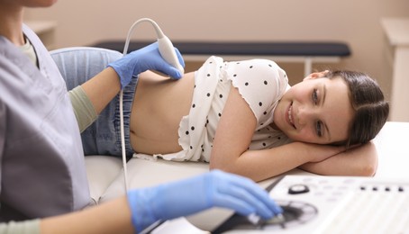 Photo of Sonographer conducting girl's renal ultrasound examination in clinic, closeup