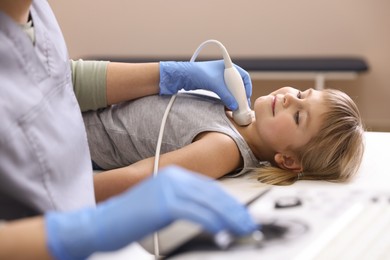 Photo of Sonographer conducting ultrasound examination of little girl's thyroid gland in clinic, closeup