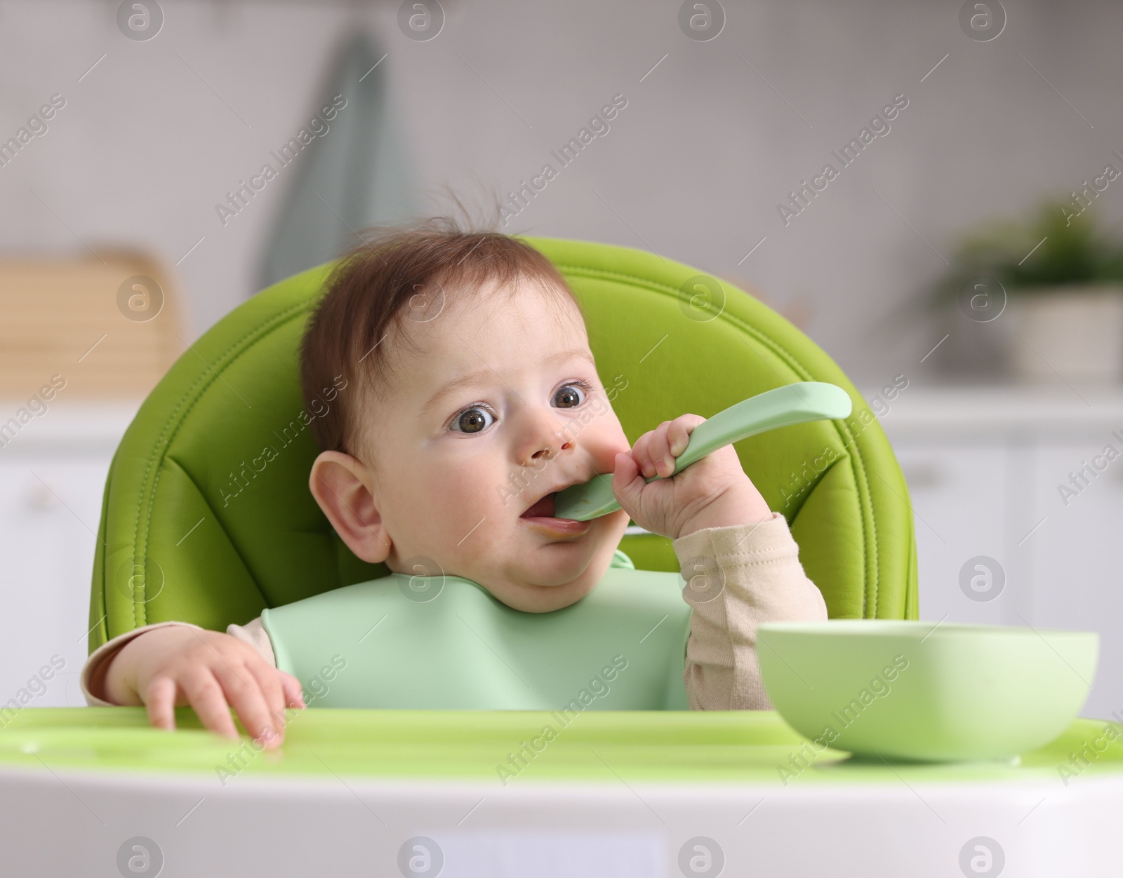 Cute little baby eating on feeding chair at home Photo of Cute little baby eating on feeding chair at home