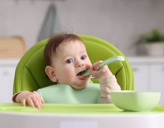 Photo of Cute little baby eating on feeding chair at home