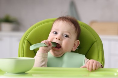 Photo of Cute little baby eating on feeding chair at home