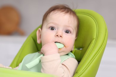 Photo of Cute little baby eating on feeding chair at home