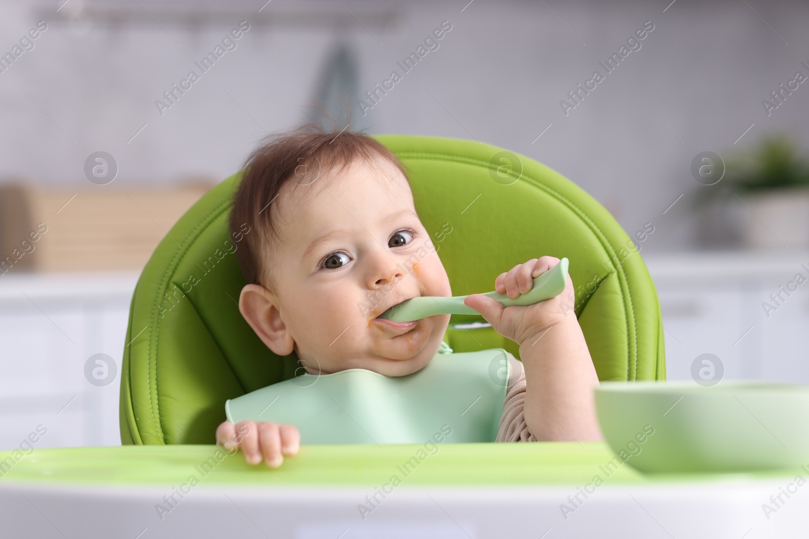 Cute little baby eating on feeding chair at home Photo of Cute little baby eating on feeding chair at home