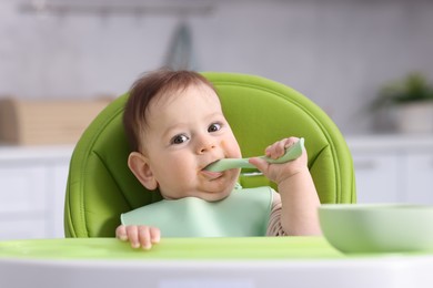 Photo of Cute little baby eating on feeding chair at home