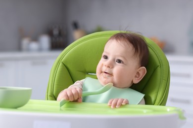 Photo of Cute little baby eating on feeding chair at home
