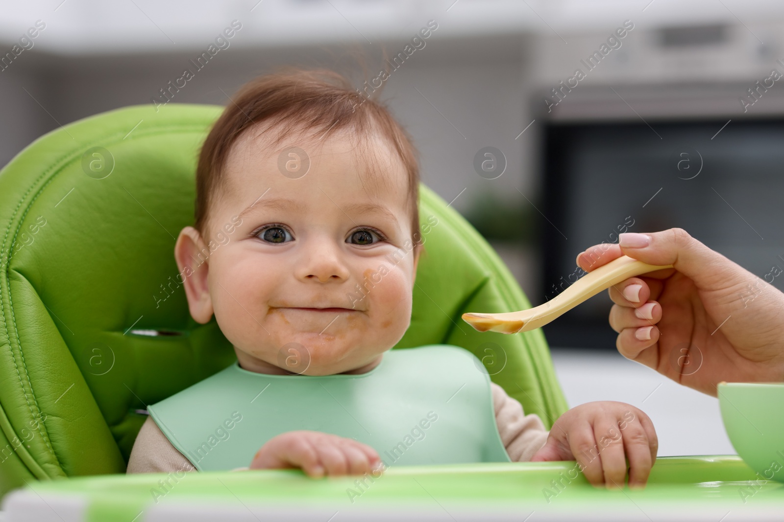 Mother feeding her baby on chair at home, closeup Photo of Mother feeding her baby on chair at home, closeup
