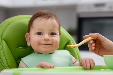 Photo of Mother feeding her baby on chair at home, closeup