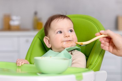 Photo of Mother feeding her baby on chair at home, closeup