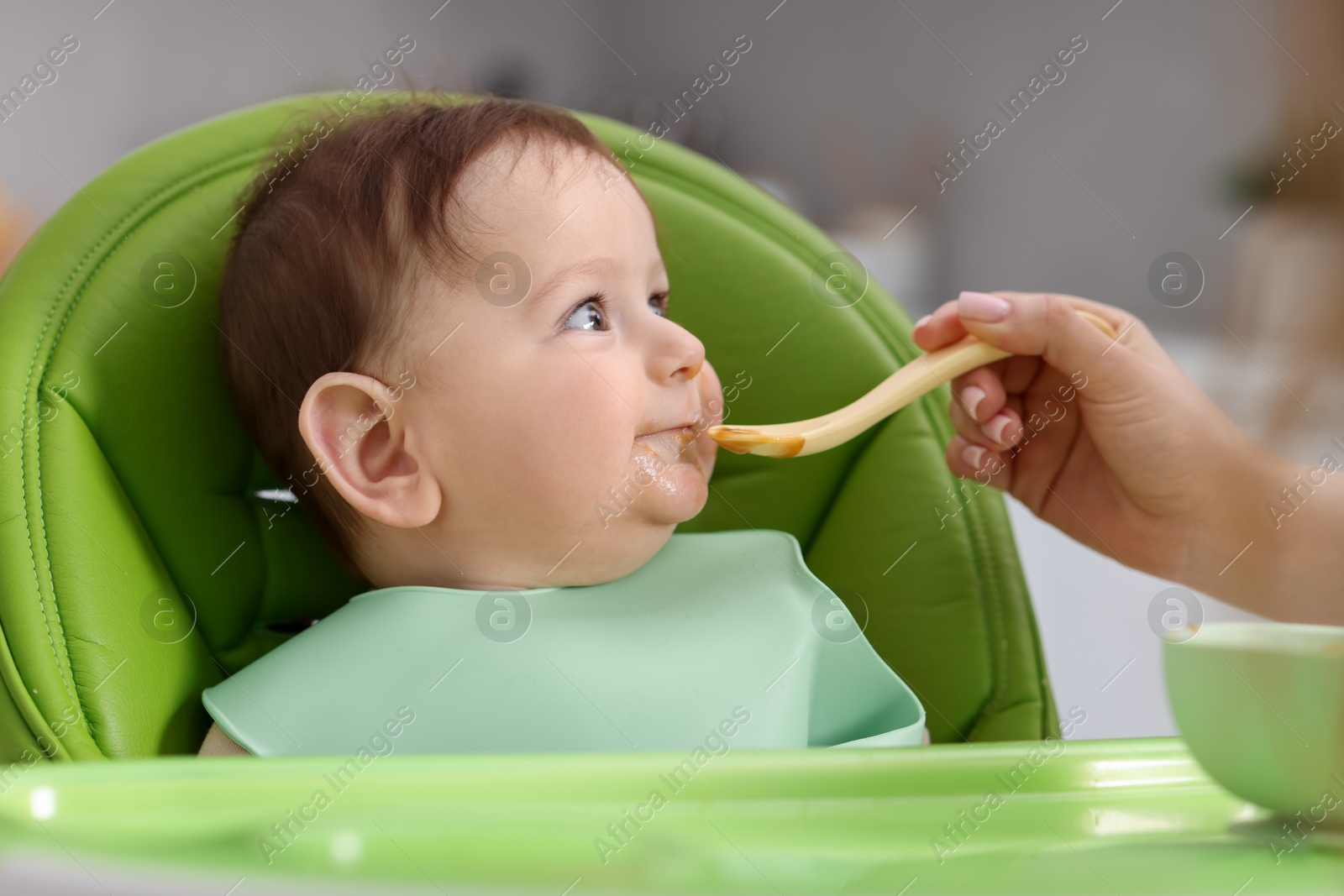 Mother feeding her baby on chair at home, closeup Photo of Mother feeding her baby on chair at home, closeup