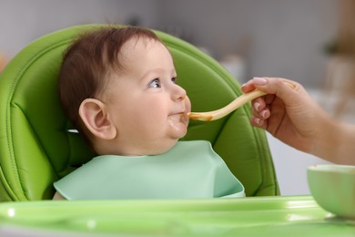 Photo of Mother feeding her baby on chair at home, closeup