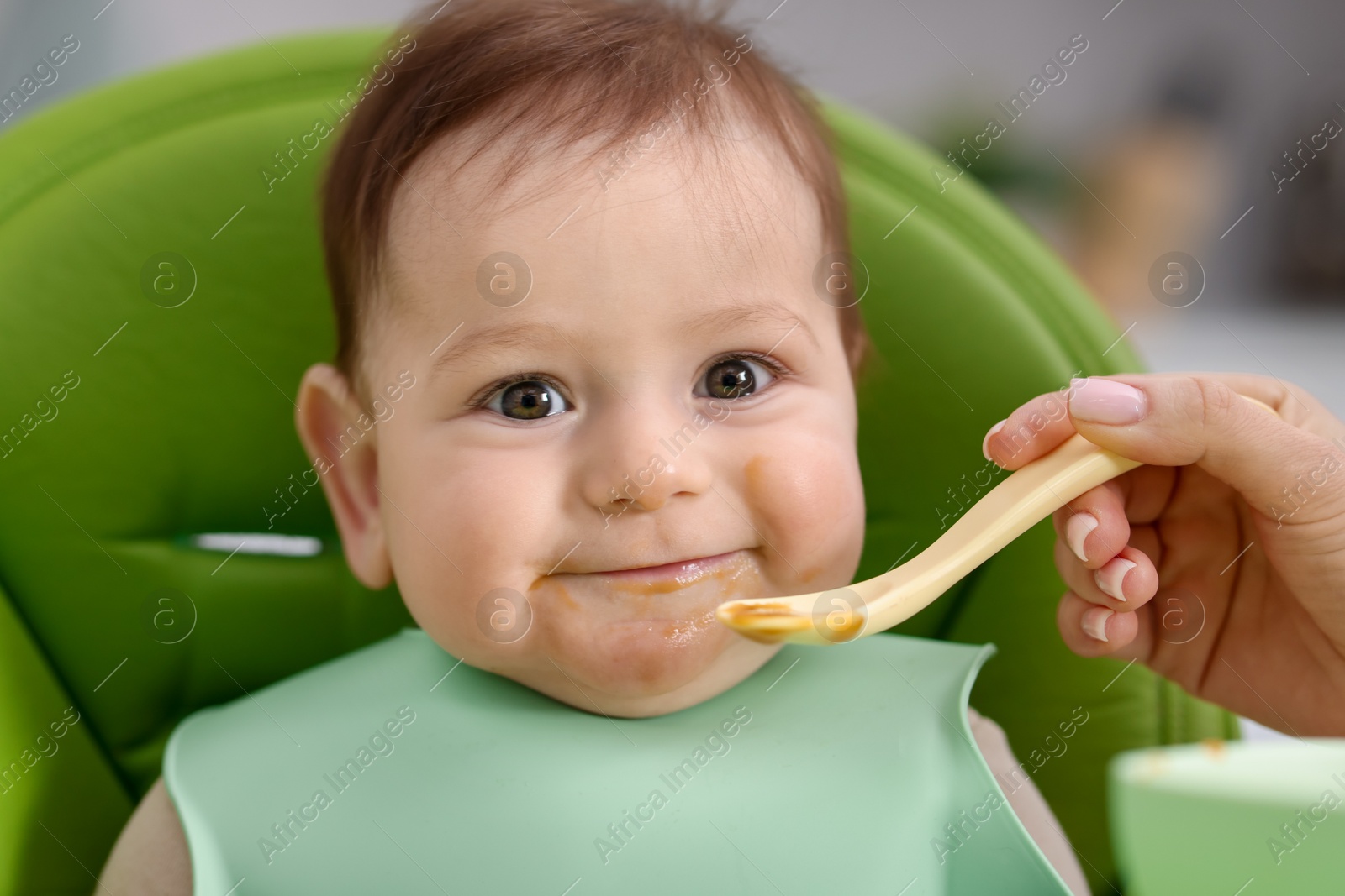 Mother feeding her baby on chair at home, closeup Photo of Mother feeding her baby on chair at home, closeup