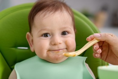 Photo of Mother feeding her baby on chair at home, closeup
