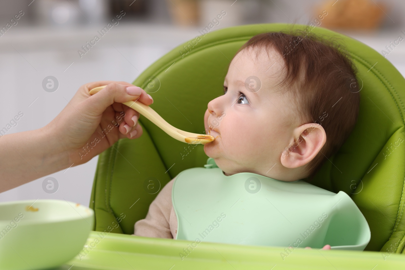 Mother feeding her baby on chair at home, closeup Photo of Mother feeding her baby on chair at home, closeup