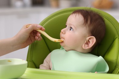Photo of Mother feeding her baby on chair at home, closeup
