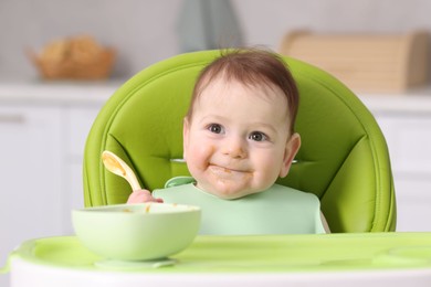Photo of Cute little baby eating on feeding chair at home