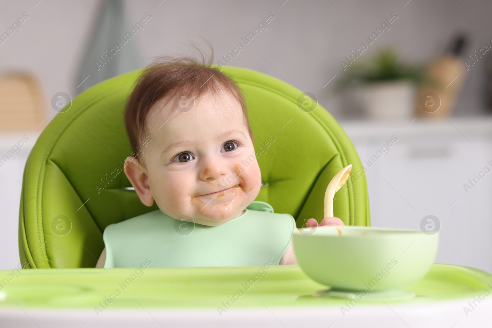 Cute little baby eating on feeding chair at home Photo of Cute little baby eating on feeding chair at home