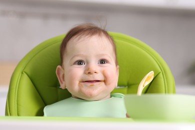 Photo of Cute little baby eating on feeding chair at home