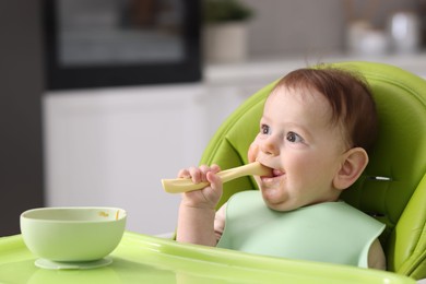 Photo of Cute little baby eating on feeding chair at home. Space for text