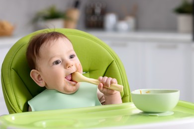 Photo of Cute little baby eating on feeding chair at home