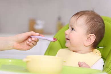 Photo of Mother feeding her baby on chair at home, closeup