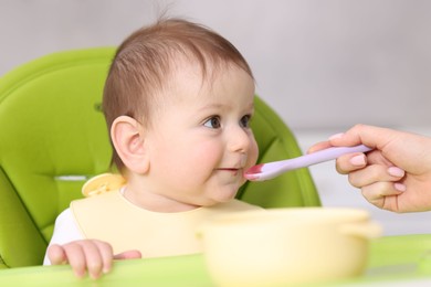 Photo of Mother feeding her baby on chair at home, closeup