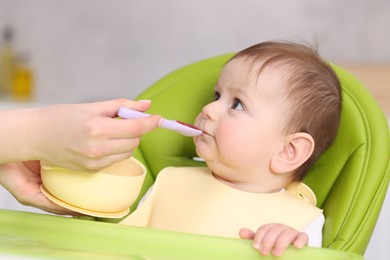 Photo of Mother feeding her baby on chair at home, closeup