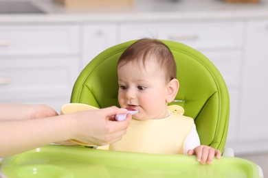 Photo of Mother feeding her baby on chair at home, closeup