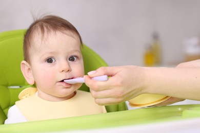 Photo of Mother feeding her baby on chair at home, closeup