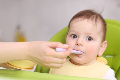 Photo of Mother feeding her baby on chair at home, closeup