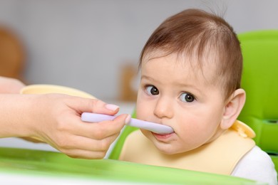 Photo of Mother feeding her baby on chair at home, closeup