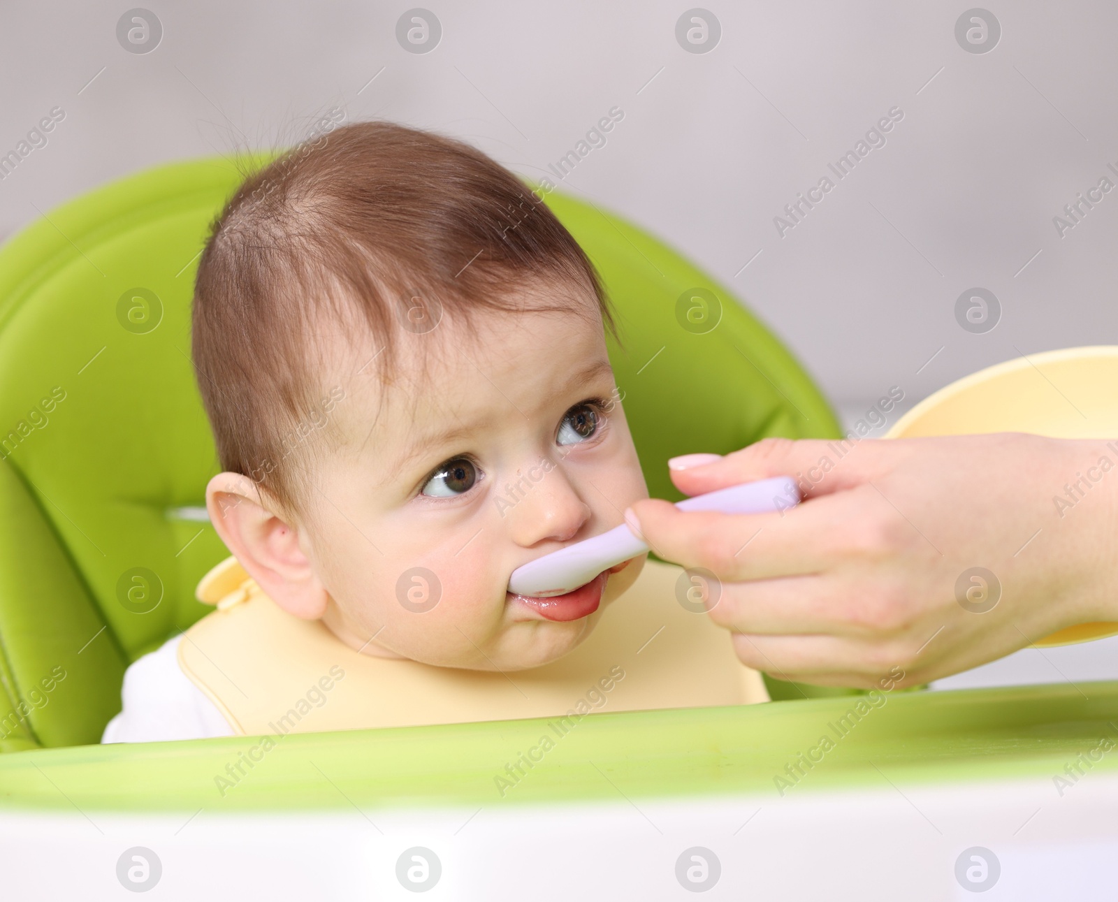 Mother feeding her baby on chair at home, closeup Photo of Mother feeding her baby on chair at home, closeup