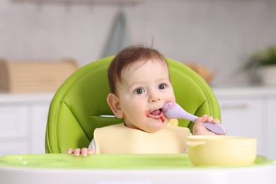 Photo of Cute little baby eating on feeding chair at home