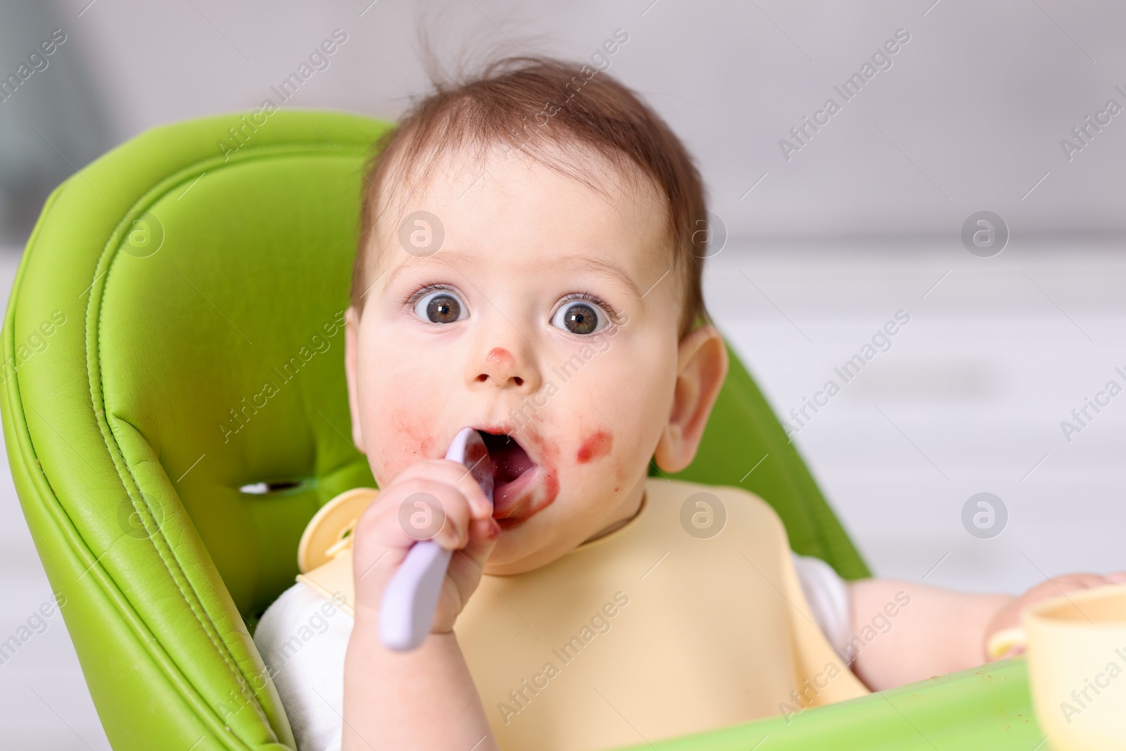 Cute little baby eating on feeding chair at home Photo of Cute little baby eating on feeding chair at home
