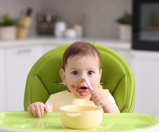 Photo of Cute little baby eating on feeding chair at home