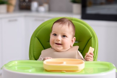 Photo of Cute little baby eating on feeding chair at home