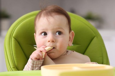Photo of Cute little baby eating on feeding chair at home