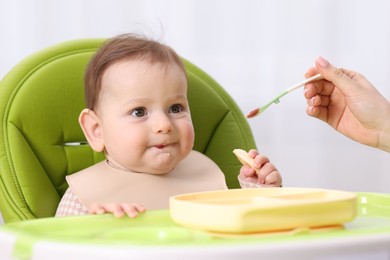 Photo of Mother feeding her baby on chair at home, closeup