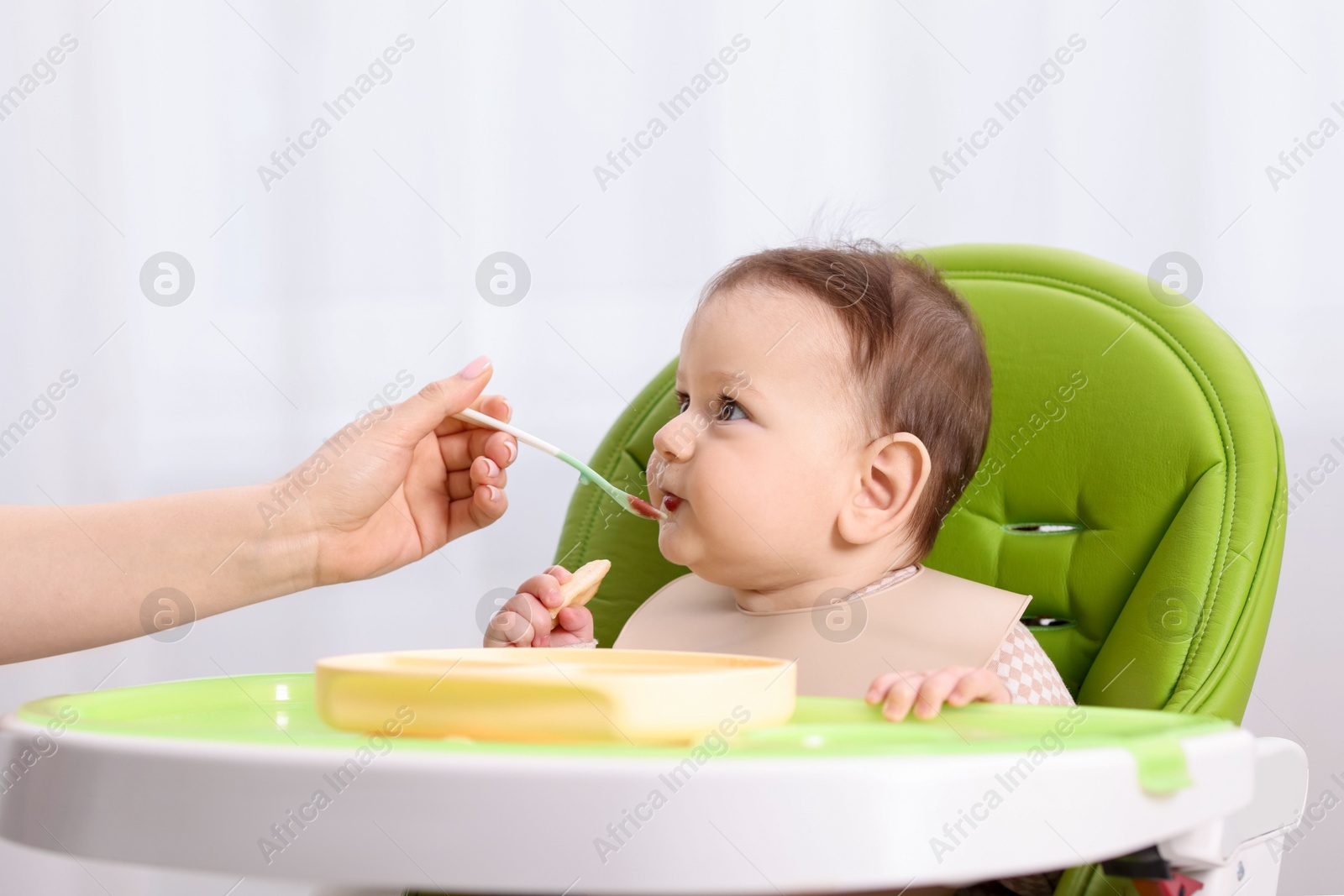 Mother feeding her baby on chair at home, closeup Photo of Mother feeding her baby on chair at home, closeup