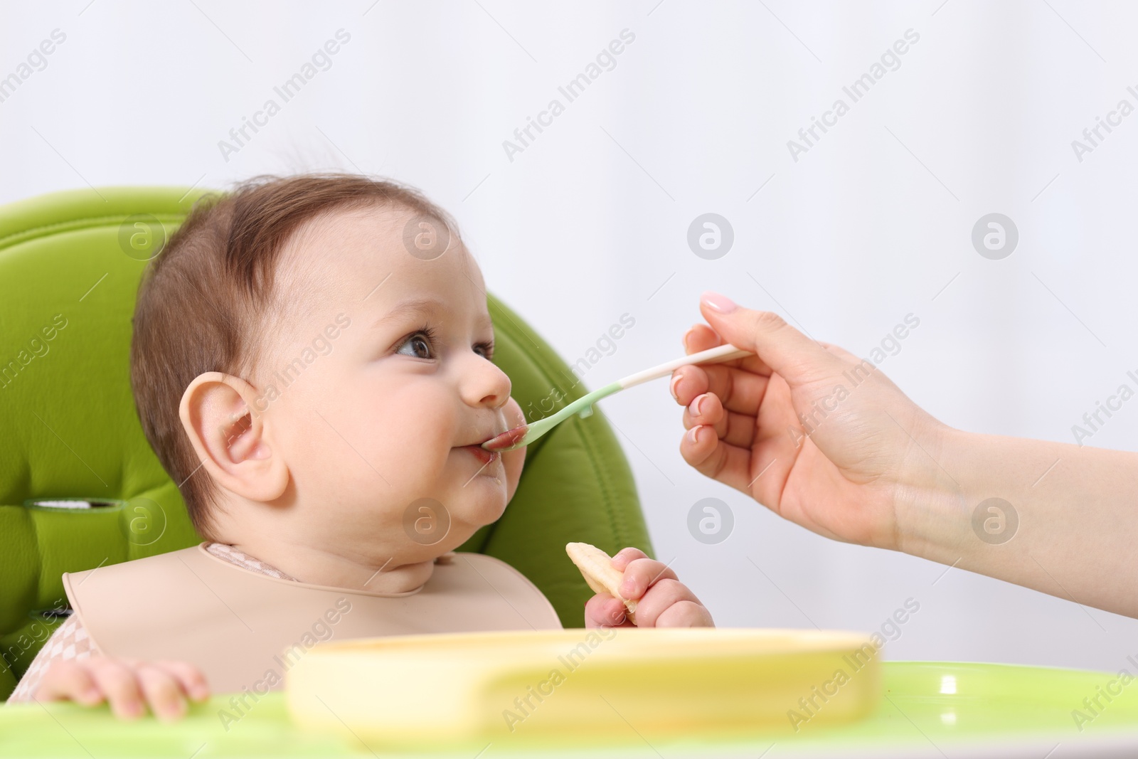 Mother feeding her baby on chair at home, closeup Photo of Mother feeding her baby on chair at home, closeup